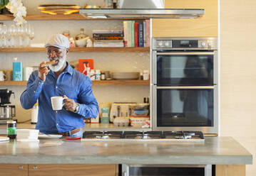 Mann genießt Toast und Kaffee zum Frühstück in einer modernen Küche - HOXF06388