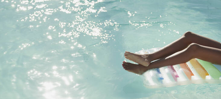 Unbekümmerte junge Frau auf einem Floß im sonnigen, ruhigen Schwimmbad - HOXF06406
