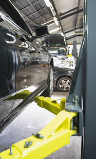 Car on hydraulic lift in auto repair shop - HOXF06464