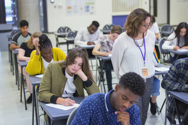 Gymnasiallehrer beaufsichtigt Schüler, die eine Prüfung ablegen, im Klassenzimmer - CAIF27971