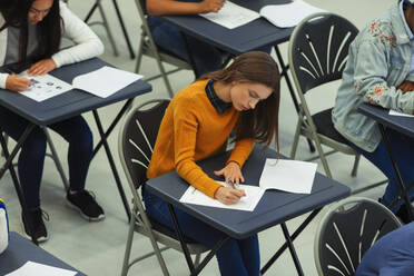 Konzentrierte Schülerin, die am Schreibtisch im Klassenzimmer eine Prüfung ablegt - CAIF27978