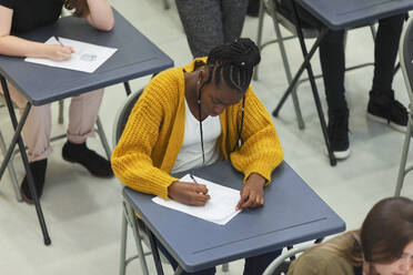 Konzentrierte Schülerin, die am Schreibtisch im Klassenzimmer eine Prüfung ablegt - CAIF27981