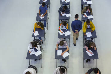 Gymnasiallehrer beaufsichtigt Schüler, die an den Pulten Prüfungen ablegen - CAIF27983