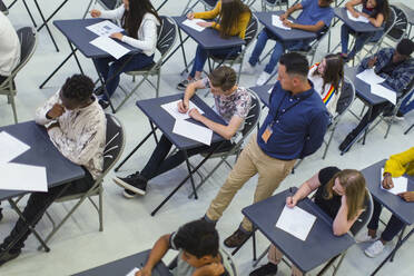 Lehrer beaufsichtigt Gymnasiasten, die an den Tischen Prüfungen ablegen - CAIF27991