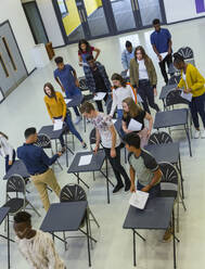 Blick von oben auf Gymnasiasten, die ihre Prüfung an den Tischen beenden - CAIF28000