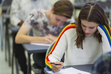 Konzentrierte Schülerin, die am Schreibtisch im Klassenzimmer eine Prüfung ablegt - CAIF28003