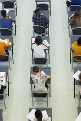 Blick von oben auf Gymnasiasten, die an den Tischen im Klassenzimmer eine Prüfung ablegen - CAIF28011