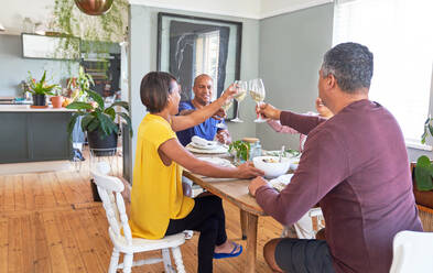 Freunde genießen das Mittagessen und stoßen mit Weingläsern an - CAIF28026