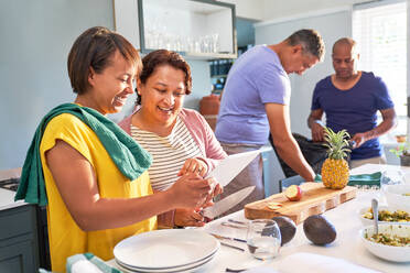 Happy couple friends using digital tablet and cooking in kitchen - CAIF28032