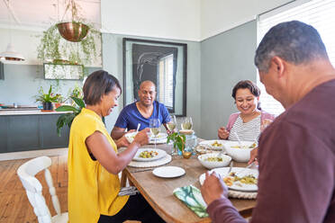 Happy mature couple friends eating lunch at dining table - CAIF28102