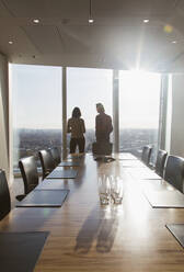 Geschäftsleute stehen am sonnigen Konferenzraumfenster - CAIF28114