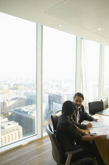 Geschäftsleute besprechen Papierkram in einem Konferenzraum in einem Hochhaus - CAIF28125