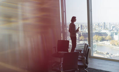 Thoughtful businessman standing at highrise office window - CAIF28147