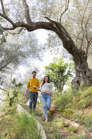 Glückliches Paar, das auf einer Treppe inmitten von Pflanzen auf dem Lande spazieren geht, lizenzfreies Stockfoto