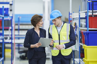 Supervisor and female manager discussing over clipboard in factory - RORF02169