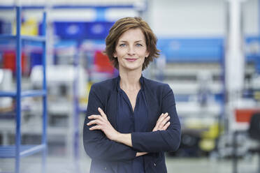 Confident female manager standing arms crossed in factory - RORF02170