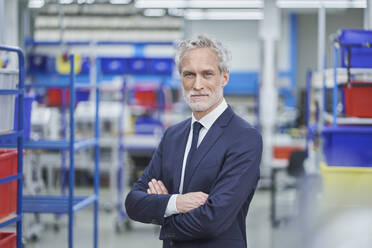 Confident male manager standing arms crossed in factory - RORF02171