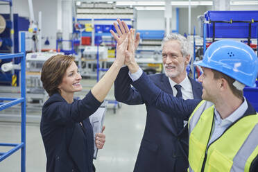 Happy managers and supervisor giving high-five in factory - RORF02175
