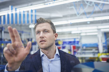 Männlicher Vorgesetzter berührt Graphen auf Glas in einer Fabrik - RORF02178