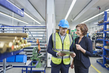 Supervisor and female manager discussing over digital tablet in industry - RORF02195
