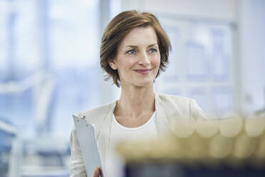 Thoughtful female manager holding clipboard in factory - RORF02206