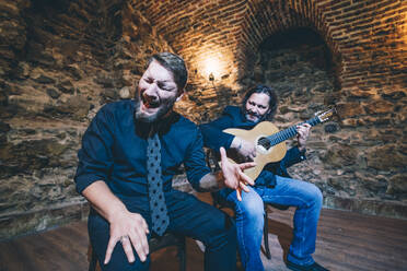 Mann spielt Flamenco auf der Gitarre, während die Sängerin in einem Nachtclub singt - OCMF01322