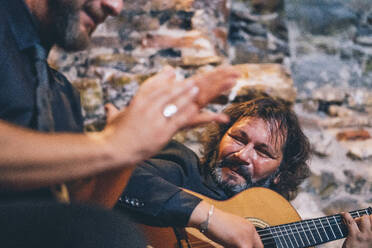 Gitarrist spielt Flamenco auf der Gitarre, während die Sängerin im Club in die Hände klatscht - OCMF01331