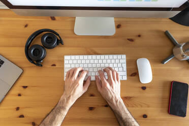 Hände eines Mannes, der von zu Hause aus arbeitet, Blick von oben auf den Schreibtisch mit mobilen Geräten und Kaffeemaschine - WPEF02983