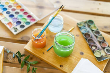Aquarellfarben mit Wasser und Pinseln auf Holztisch zu Hause - AFVF06494