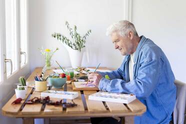 Älterer Mann malt auf dem Tisch zu Hause - AFVF06505