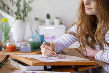 Cropped image of young woman painting on paper at home - AFVF06533