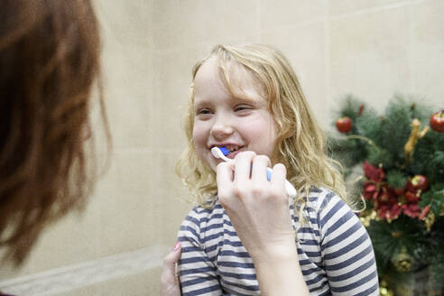 Ausgeschnittenes Bild einer Frau, die ihrer Tochter beim Zähneputzen zu Hause hilft - EYAF01111
