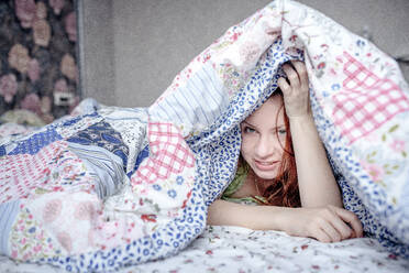 Schöne Frau liegt unter der Bettdecke im Bett zu Hause - EYAF01115