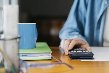 Senior man holding calculator while working at table - AFVF06545