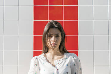 Schöne junge Frau an einer gefliesten Wand an einem sonnigen Tag - MTBF00427