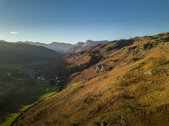 Aerial view of large mountains surrounding a village in Elterwater, Ambleside, UK - AAEF08680