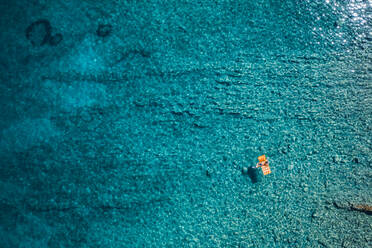 Aerial view of a woman swimming in the turquoise waters of Stara Baska, Croatia - AAEF08783