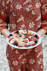 Close-up of young woman holding fruits in plate while standing outdoors - ALBF01250