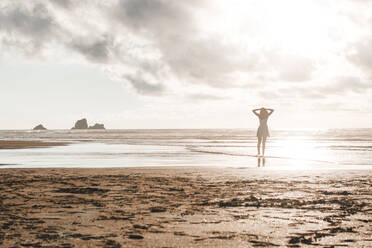 Silhouette woman standing at beach against cloudy sky during sunset - FVSF00390