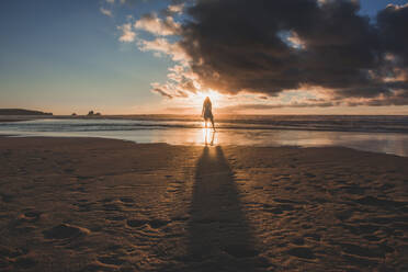 Silhouette junge Frau steht am Strand gegen den Himmel bei Sonnenuntergang - FVSF00398