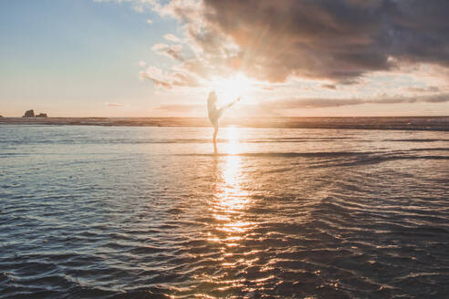 Silhouette Frau tanzend im Meer stehend gegen den Himmel bei Sonnenuntergang - FVSF00399