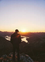 Männlicher Tourist steht bei Sonnenuntergang auf einem Berg, Leon, Spanien - FVSF00411
