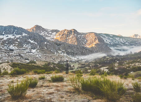 Mann in einer Landschaft vor felsigen Bergen, Leon, Spanien - FVSF00421