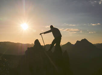 Silhouette male hiker standing with hiking pole on mountain during sunset, Leon, Spain - FVSF00422