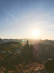 Männlicher Wanderer sitzt bei Sonnenuntergang auf einer Klippe gegen den Himmel, Leon, Spanien - FVSF00425