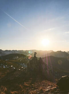 Männlicher Wanderer sitzt bei Sonnenuntergang auf einer Klippe gegen den Himmel, Leon, Spanien - FVSF00425