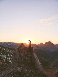 Männlicher Wanderer sitzt bei Sonnenuntergang auf einer Klippe, Leon, Spanien - FVSF00427