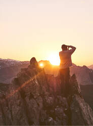 Männlicher Tourist, der während des Sonnenuntergangs auf einer Klippe steht und fotografiert, Leon, Spanien - FVSF00428