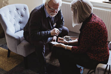 High angle view of senior woman showing mobile phone to man while sitting in hotel - MASF18383