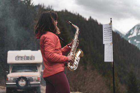 Eine Frau steht auf einem Berg im Squamish Valley, British Columbia, Kanada, und spielt Saxophon. - ISF24187
